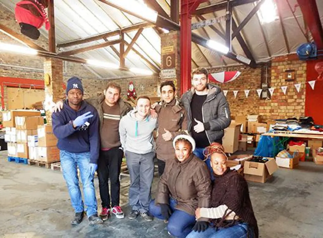 Gemeinsam mit Flüchtlingen helfen die Alpensped-Mitarbeiter bei der Kleidersortierung