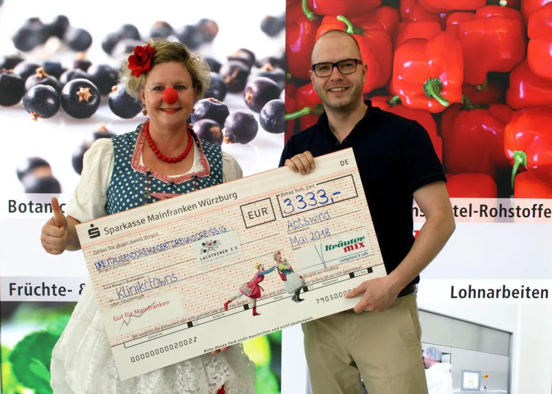 Geschäftsführer Bernhard Mix überreicht den Spendenscheck an Klinikclown Schlawine.