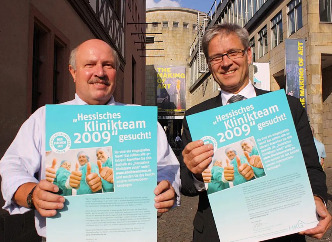 Holger Strehlau, Präsident der Hessischen Krankenhausgesellschaft (rechts), und Hans Ditzel, Pressesprecher der Hessischen Krankenhausgesellschaft, präsentieren das Plakat zur Suche des 