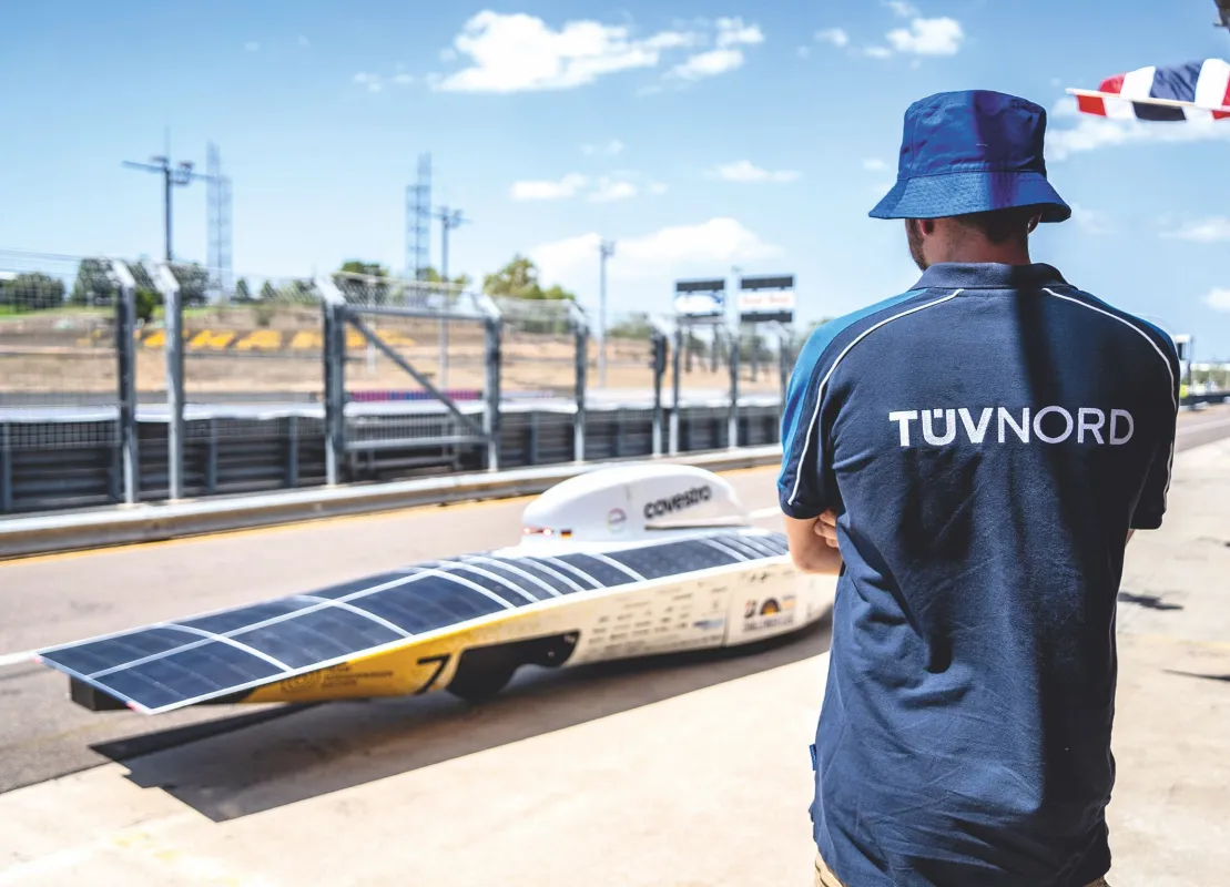Der TÜV NORD-Sachverständige Markus Machazi vor solarbetriebenem Rennwagen (© TÜV NORD Mobilität / Antonie Bauer)