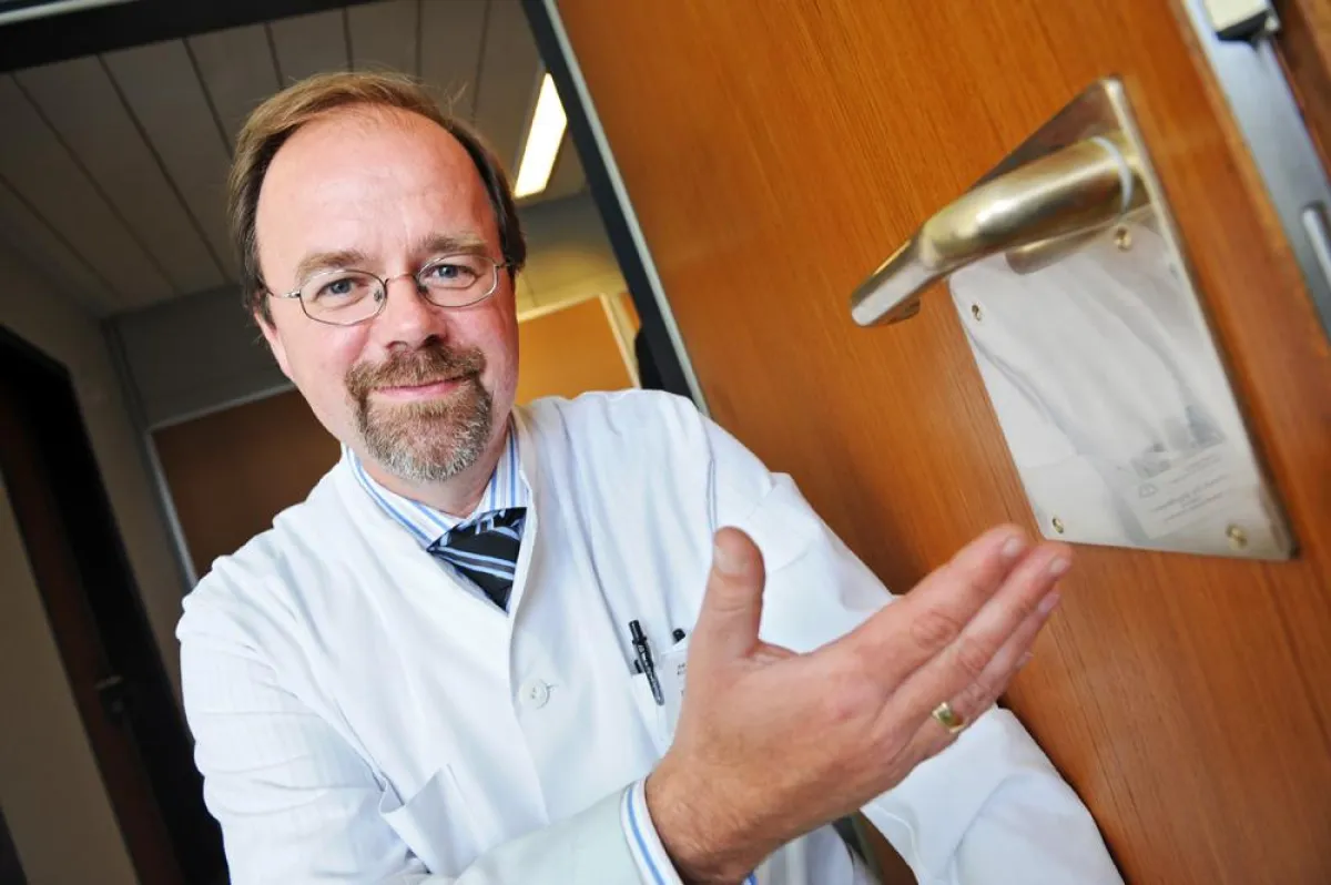 Prof. Dr. Jörg Braun mit einer Kupfer-Türklinke in der Asklepios Klinik Wandsbek