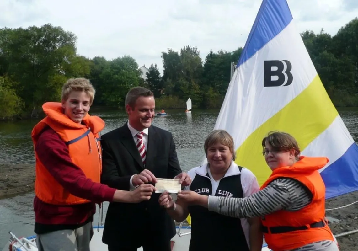 Spendenübergabe für das Steilshooper Segelprojekt: Sabine Bock, Haus der Jugend Steilshoop, und Dr. Claus Frankenstein, TÜV NORD Schulungszentrum, mit Segelkindern.