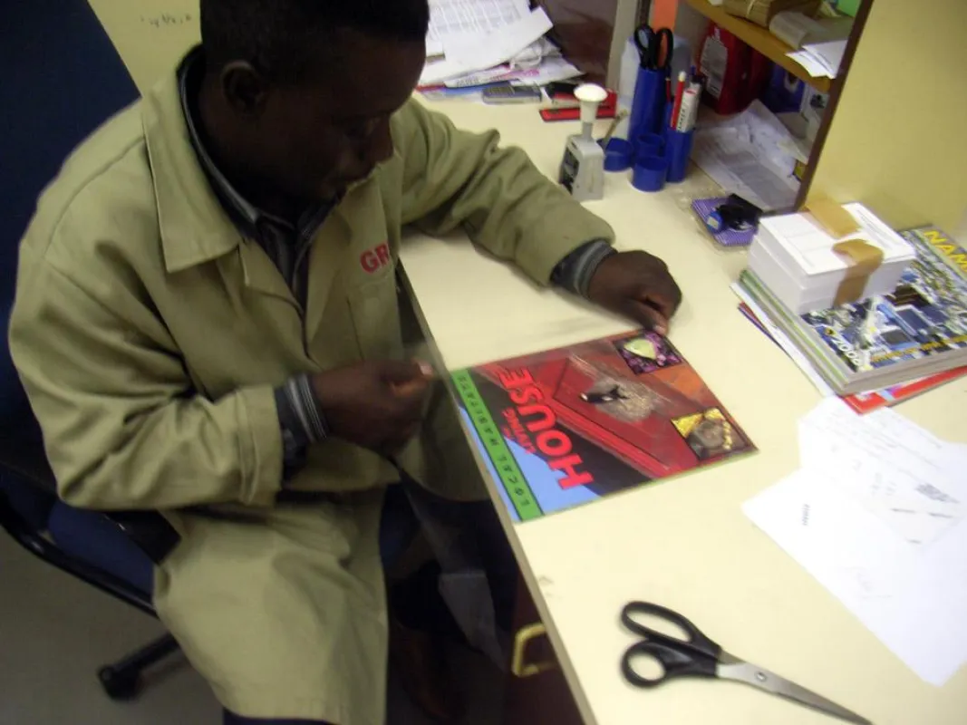 Ein Bibliotheksmitarbeiter in Namibia beim Bekleben von Büchern mit „filmolux soft PP“. Um die Folie möglichst effektiv einzusetzen und viele Bücher schützen zu können, schneiden Bibliotheksmitarbeite