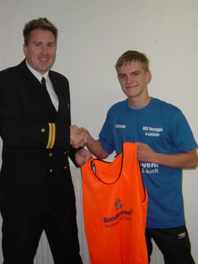 Mannschaftskapitän Marcel Wernicke nimmt die T-Shirts und Markierungshemden von Jan Kistenmacher in Empfang.