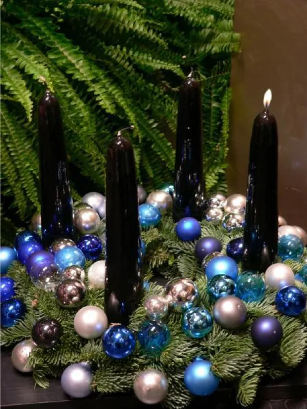 Wie kleine Perlen sehen die verschiedenfarbigen Glaskugeln auf diesem Adventsgesteck aus. Foto: Gütegemeinschaft Kerzen