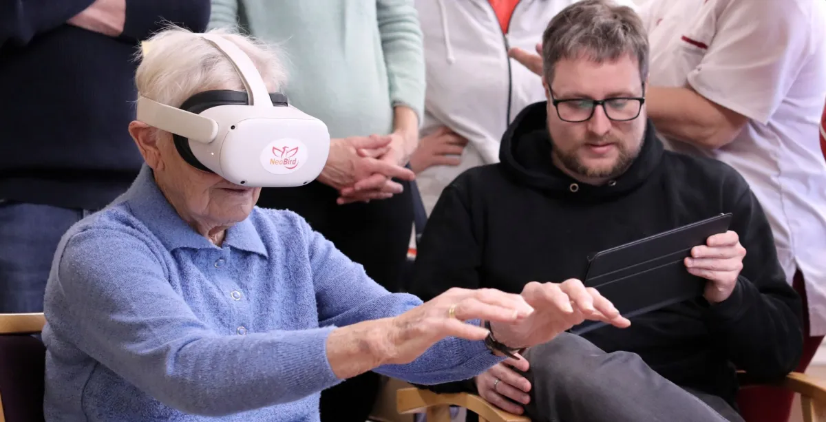 Seniorin erkundet mit einer VR-Brille verschiedene Spielstationen (© JockiFoto, Erlangen)