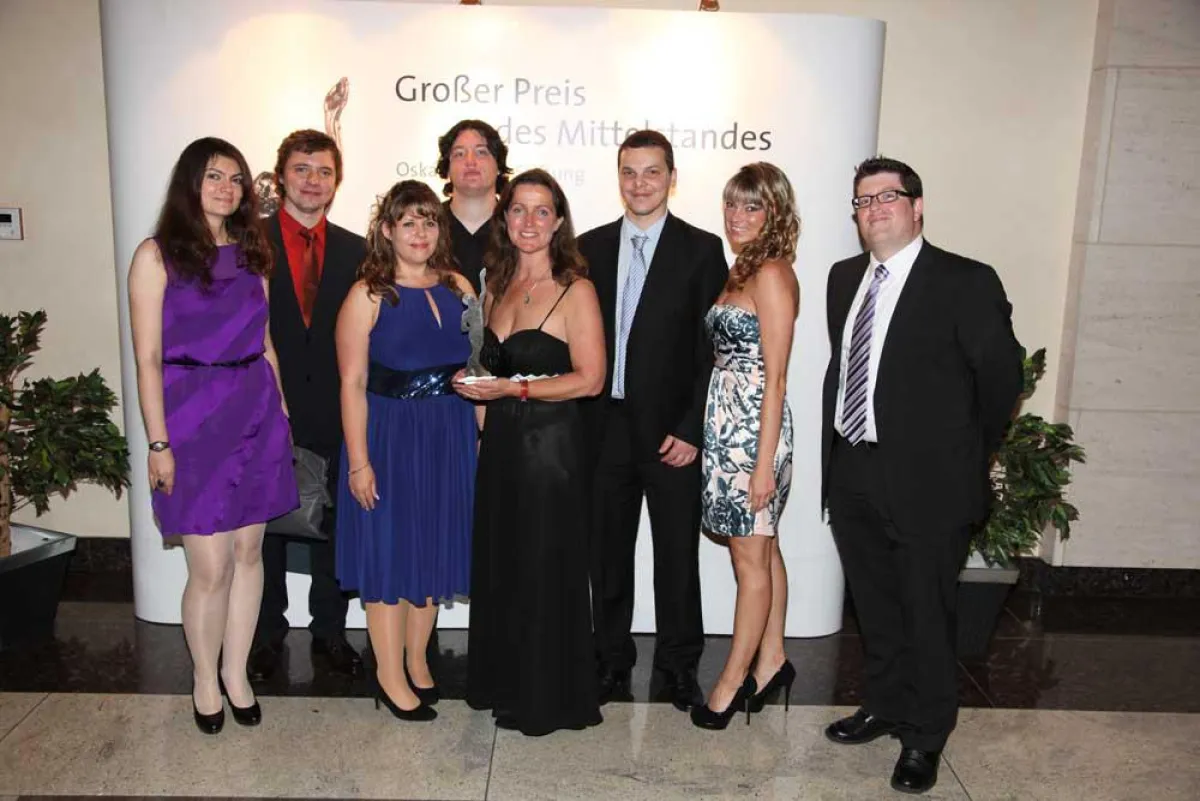 Geschäftsführerin Dr. Elisabeth Decker (Mitte, mit Award) im Kreis einiger Team-Mitglieder