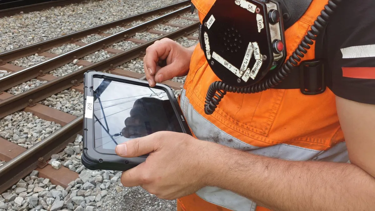 Der Rangierer am Gleis erhält seine Arbeitsaufträge für den angekommenen Zug auf dem mobilen Gerät.