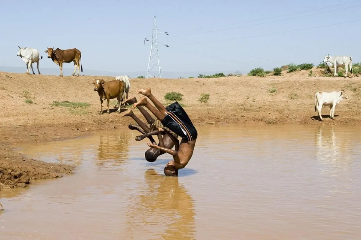 Junge Menschen freuen sich im Dorf Tula und springen in den Wasser-Pond