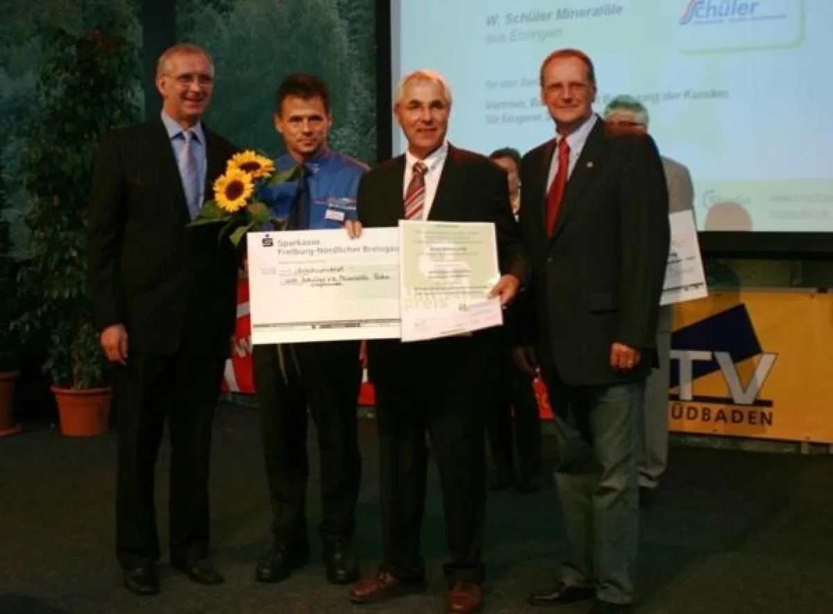 Umweltpreisverleihung in Freiburg: Bernd Dallmann (links), FWTM-Geschäftsführer, überreicht Preisurkunde und symbolischen Scheck an GF Willi Schüler (2 v. re.) und seinen Technischen Leiter Markus Gra
