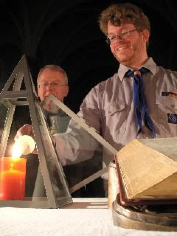 Ein Vertreter der Christlichen Pfadfinder (VCP) übergibt an den Gemeindevertreter der Zwölf-Apostel-Kirche das Friedenslicht aus Bethlehem.
