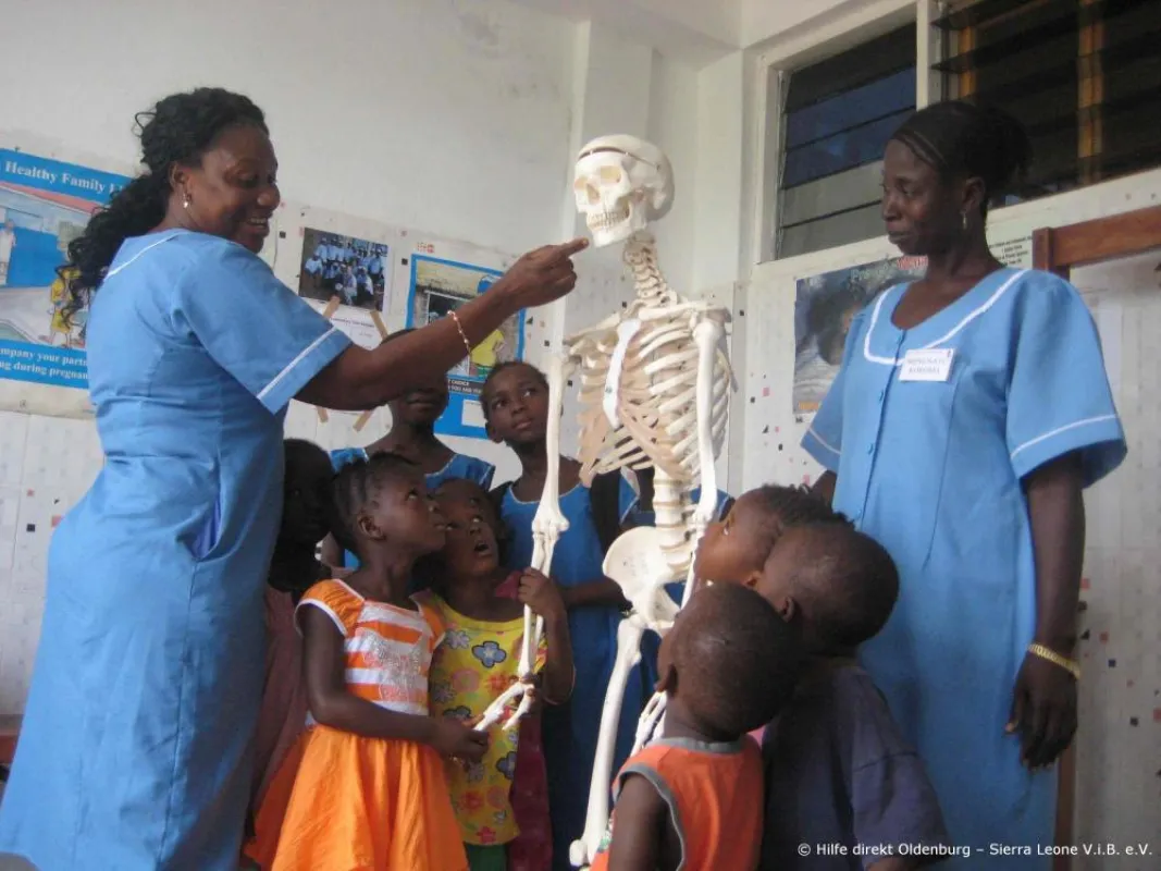 Kinder und Personal vom Gila-Hospital in Sierra Leone mit Skelettmodell