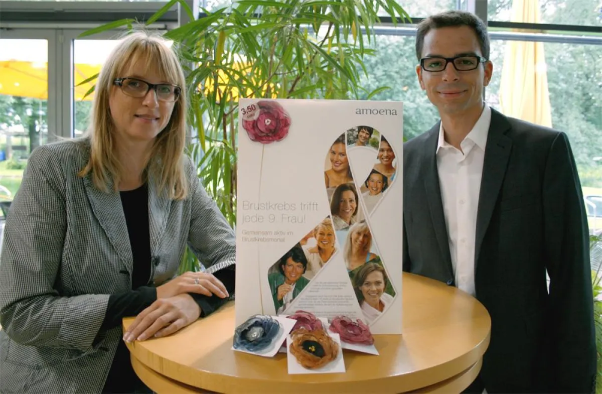 waterdrops-Geschäftsführer Mirko Hintz präsentiert Claudia Kaltenecker, Marketing Managerin bei Amoena, das Charity-Plakat.