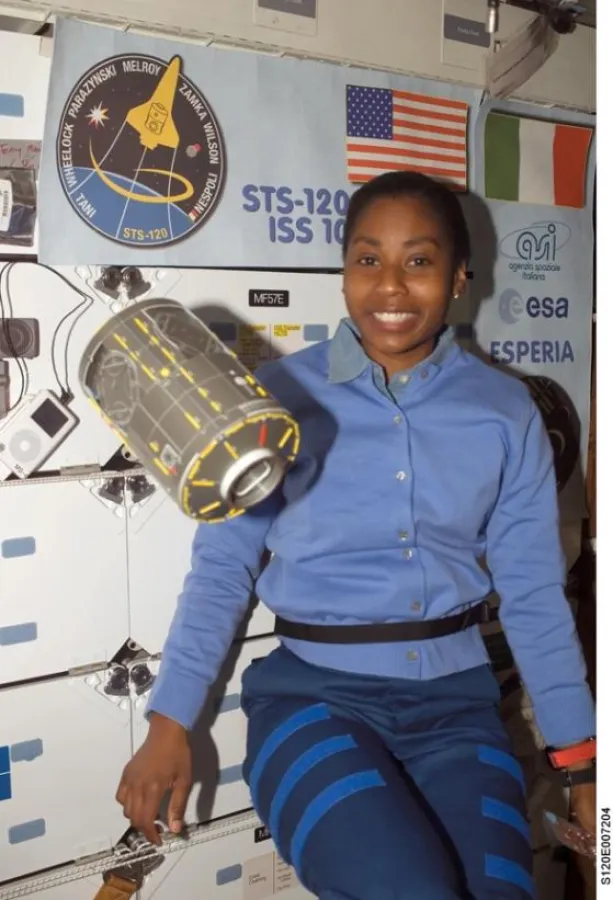Ein Modell des Harmony Verbindungsknotens fliegt schwerelos neben der Astronautin Stephanie Wilson, STS-120 Missionsspezialistin. Auf dem Mitteldeck der Discovery sind im Hintergrund zwei auf Country