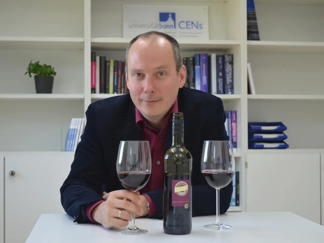 Prof. Dr. Bernd Weber vom Center for Economics and Neuroscience der Universität Bonn mit Rotwein, wie er auch bei der Verkostung der Probanden eingesetzt wurde. (© Foto: Xenia Grote)