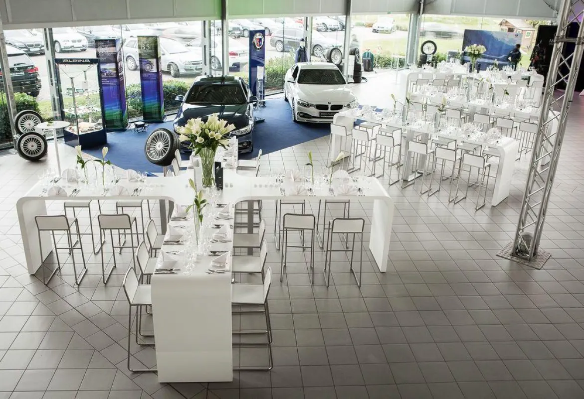 Die VIP-Gäste nahmen an kreuzförmigen Tischen vor der automobilen Kulisse Platz