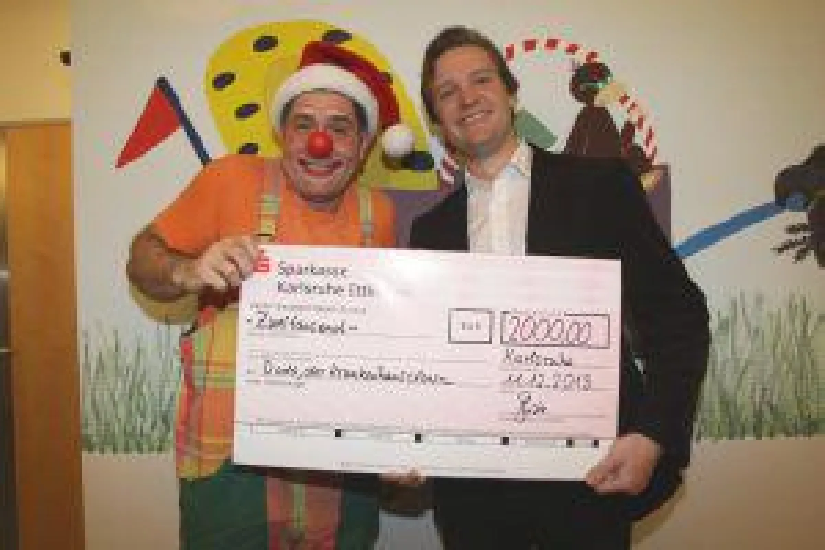 STARFACE Geschäftsführer Florian Buzin überreicht Krankenhausclown Dodo einen Scheck über 2.000 Euro