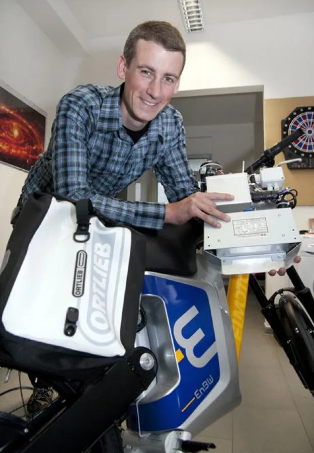 Björn Rast zeigt das Datenaufzeichnungsgerät, mit dem jedes E-Bike ausgestattet ist. Es hat eine Sim-Karte und einen GPS-Empfänger und wird in einer wasserdichten Tasche untergebracht.