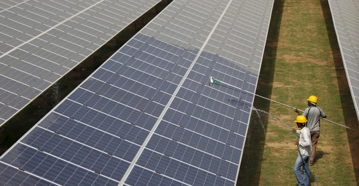 Arbeiter reinigen Photovoltaik-Module in einem Solarkraftwerk in Gujarat, Indien