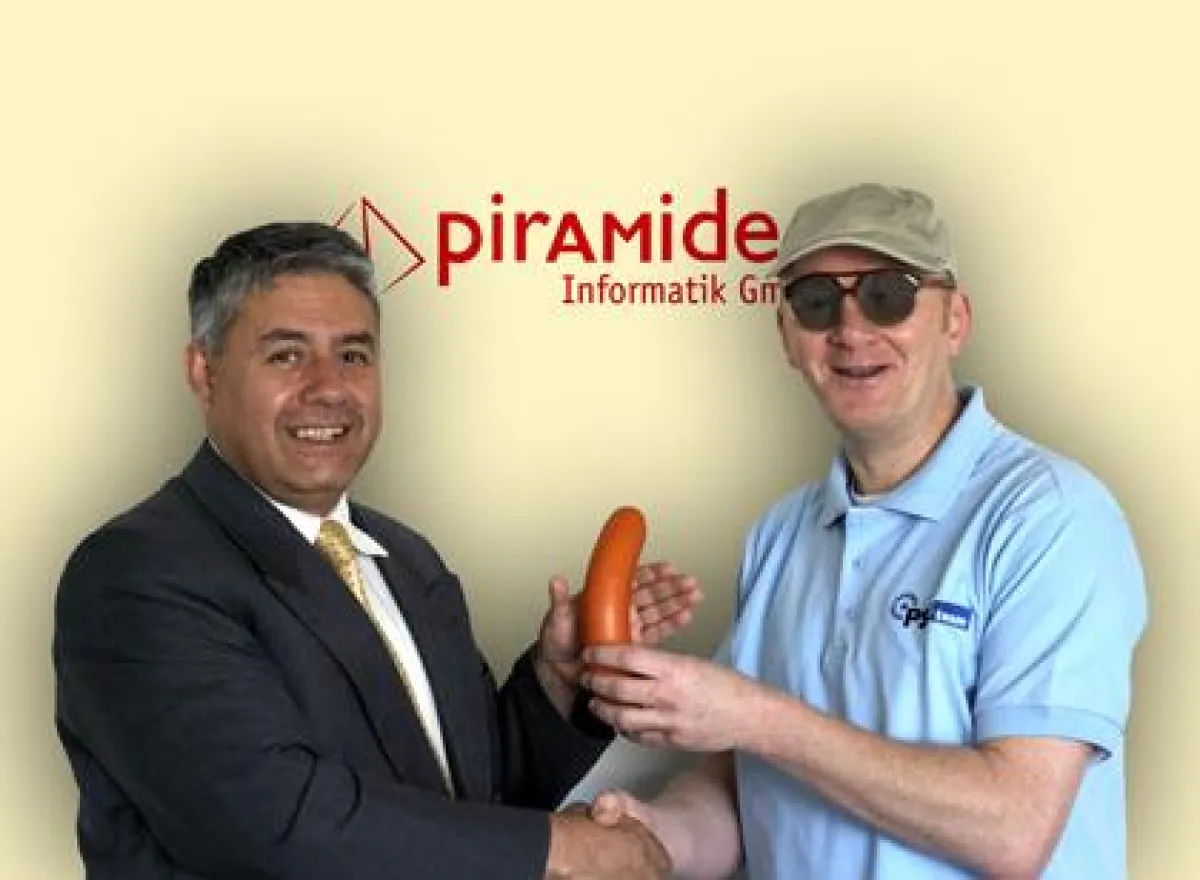 Dr. Juilo Aspiazu, Geschäftsführer der pirAMide Informatik GmbH (links) erhält zum Vertragsabschluss eine Kulturfleischwurst von Onkel Reinhold