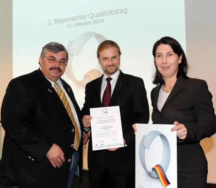 Staatssekretärin Katja Hessel und BHG-Präsident Siegfried Gallus (links) übergeben die Urkunde an André Putzlocher von der Schule