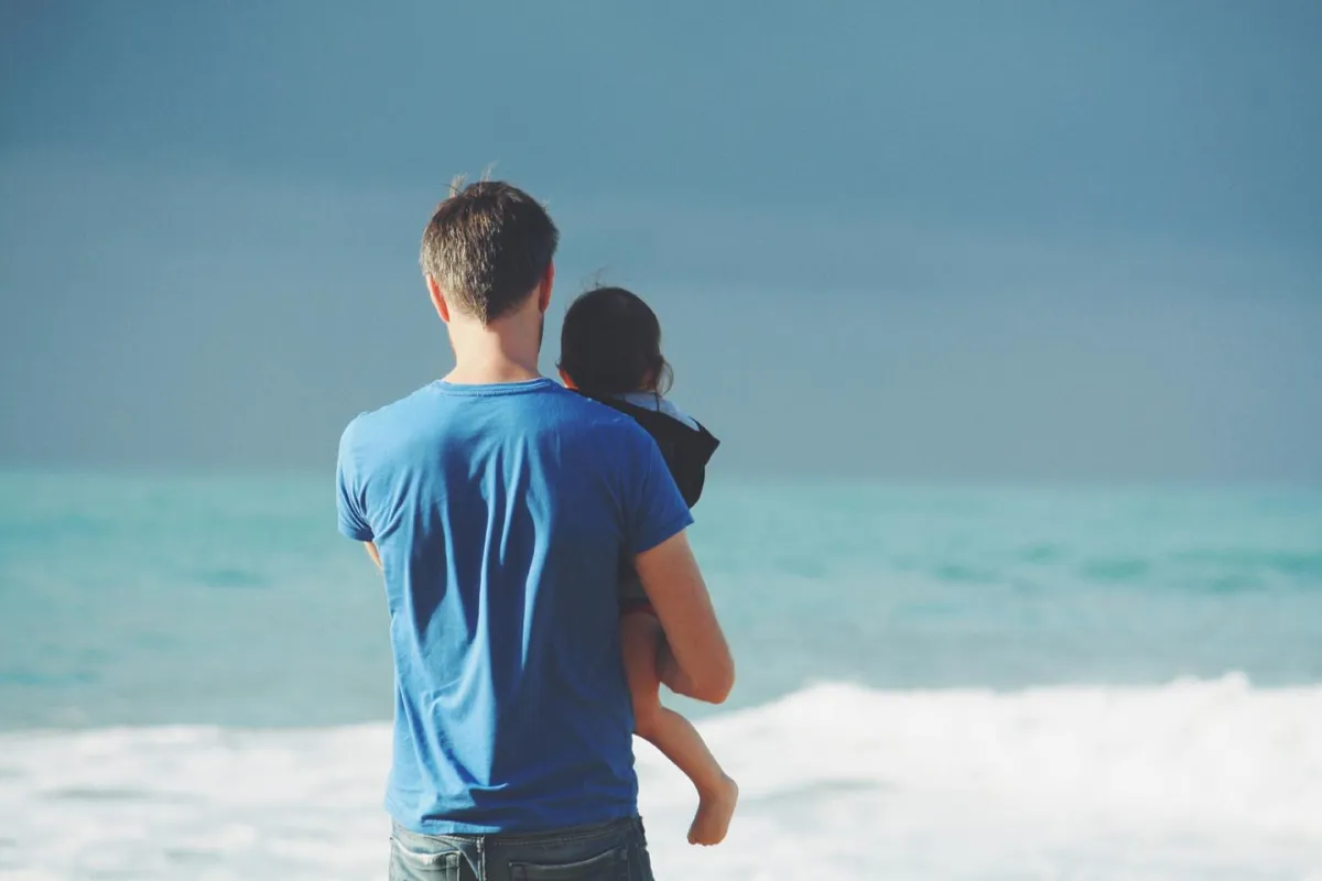 Mann mit Kind entspannt am Meer