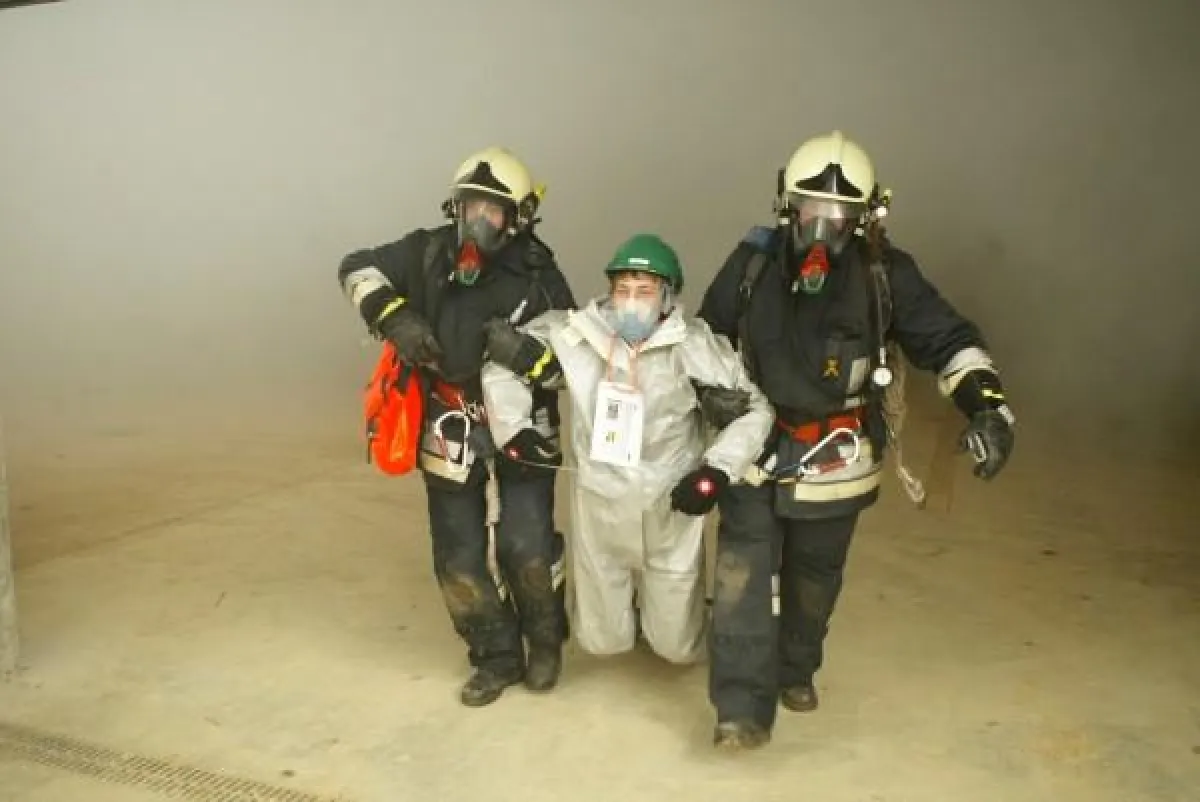 Feuerwehrmänner mit Atemschutzausrüstung retten einen Verletzten aus der Vorbereitungshalle