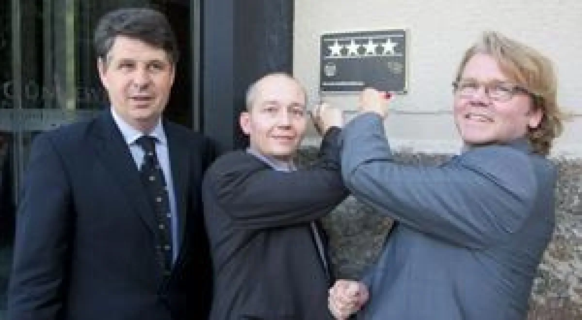 Klaus Hübenthal (r.) überreicht Hardy R. Voges (l.) und Rainer Siewert das Schild der Deutschen Hotelklassifizierung mit den vier Sternen.