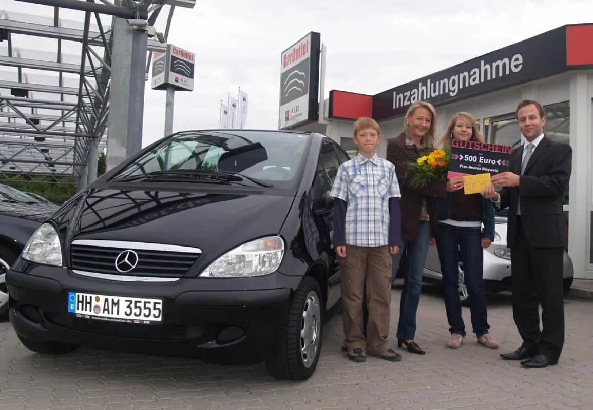 Michael Leder, Teamleiter Verkauf, (r.) übergab im CarOutlet der ALD Automotive einen Tankgutschein im Wert von 500 Euro an die Jubiläumskundin Andrea Maywald (2.v.l.) aus Hamburg.