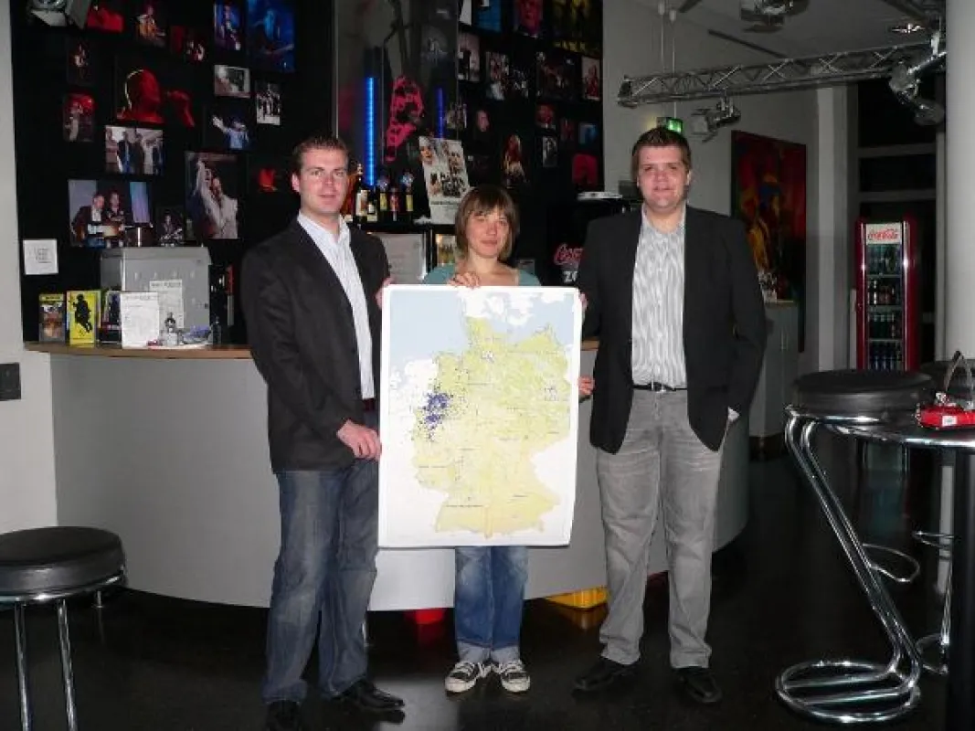 Benjamin Beloch und Sebastian Franzbach überreichen die Ergebnisse der Geomarketing Analyse an Anja Habel (rock'n'popmuseum)