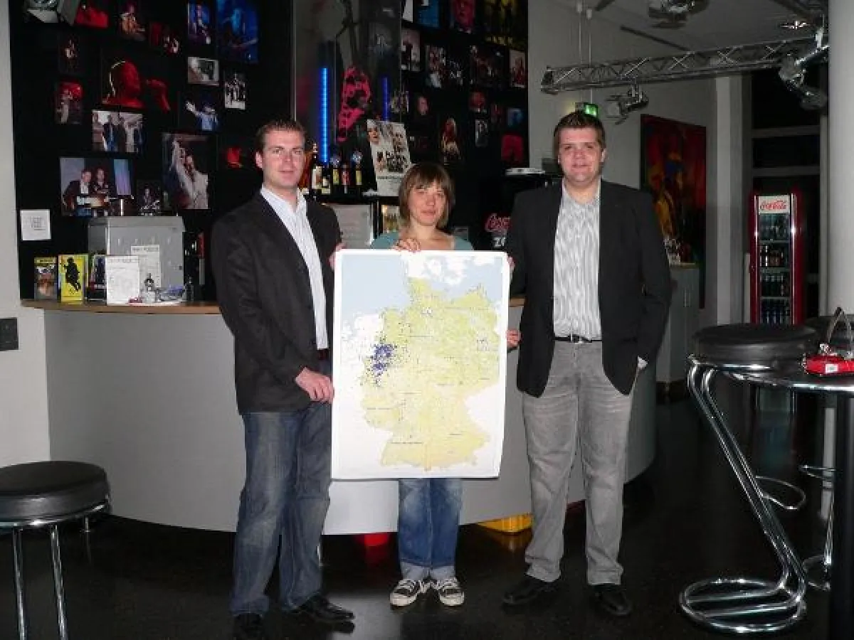 Benjamin Beloch und Sebastian Franzbach überreichen die Ergebnisse der Geomarketing Analyse an Anja Habel (rock'n'popmuseum)