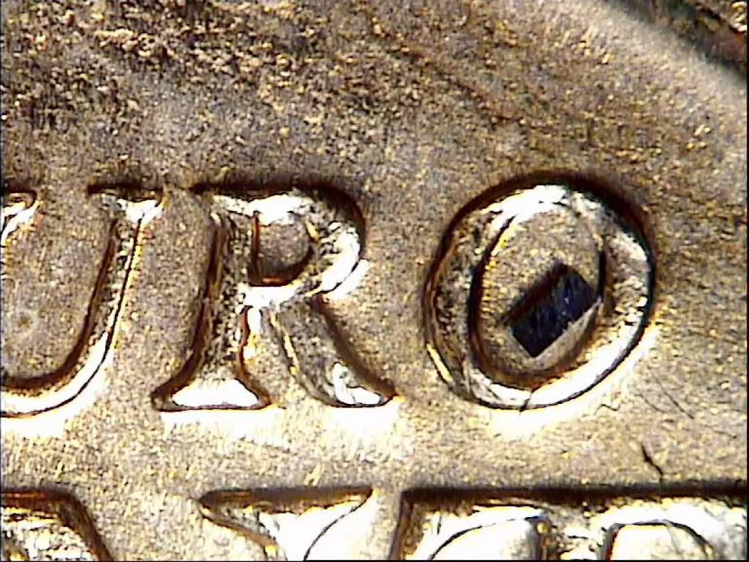 Mikroskopbild eines 03015-Bauteils, platziert auf einer Eurocent-Münze zur Darstellung der Größendim
