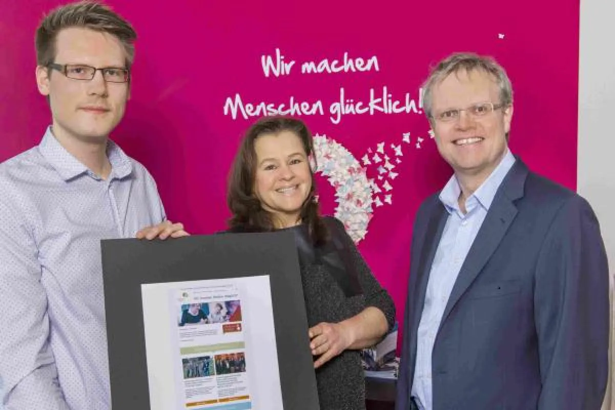 Ansgar Fulland überreicht den überarbeiteten Newsletter an Janina Krüger und Hendrik Rathmann