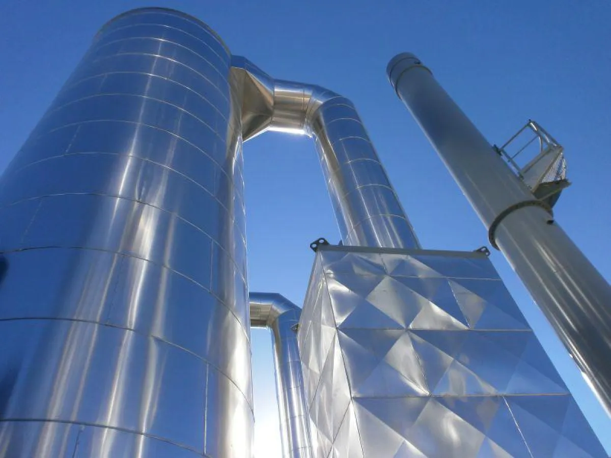 Das Foto zeigt einen Kessel in vertikaler Bauweise sowie den Kamin