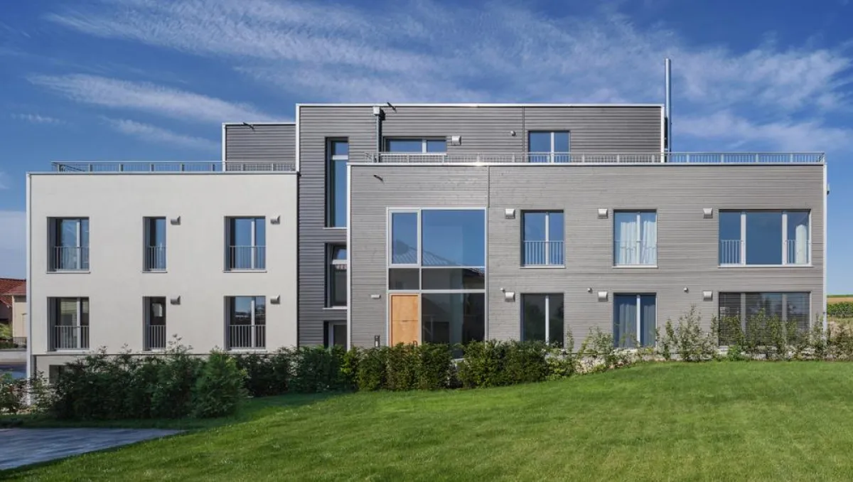 Mehrfamilienhaus Weirich mit einer Kombination aus grauer Holzverschalung und weißer Putzfassade