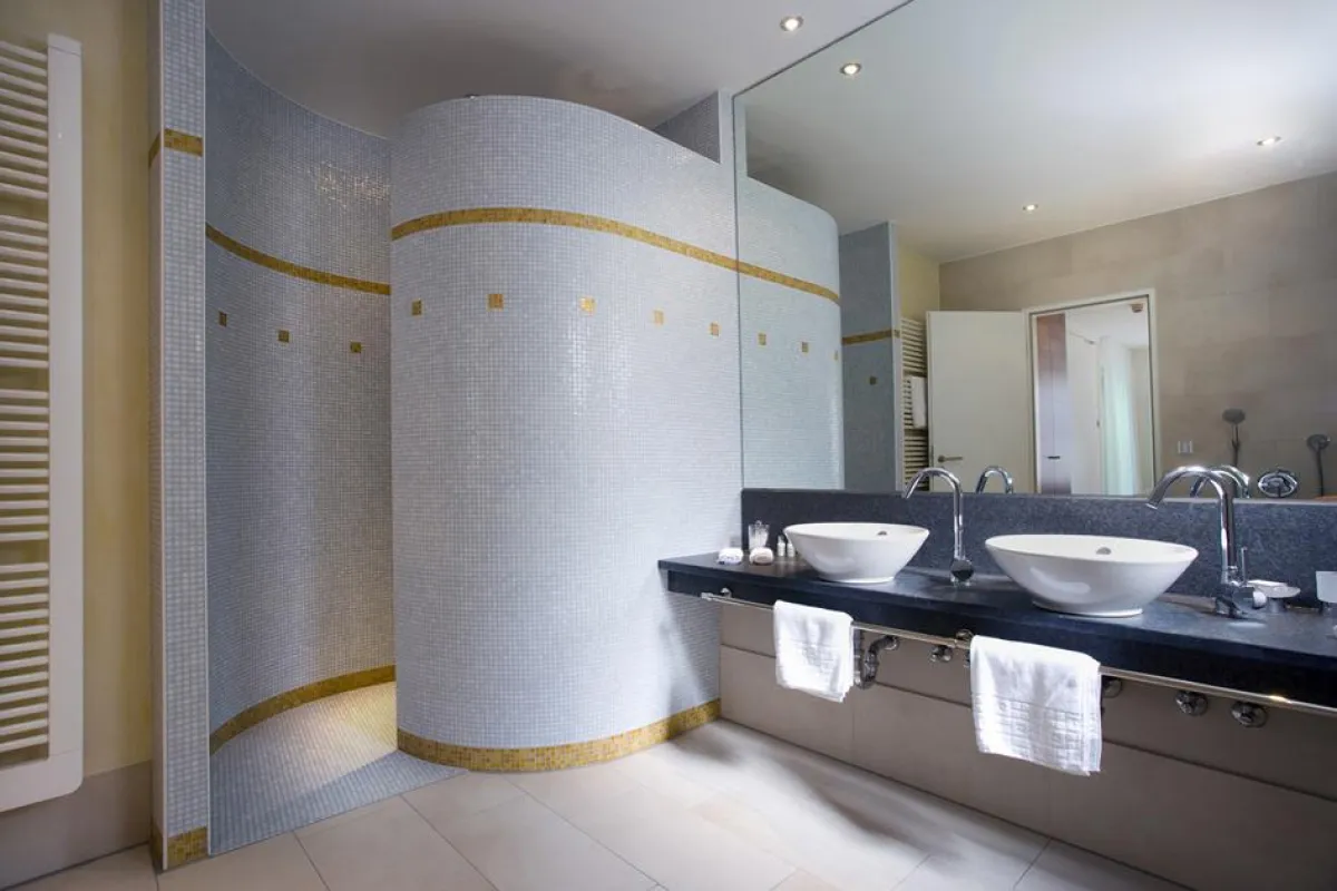 Stilvolle Details, wie weiße Mosaikfliesen oder Blattgold-Einlagen, verwandeln die Hotelbäder in außergewöhnliche Wellnessoasen.