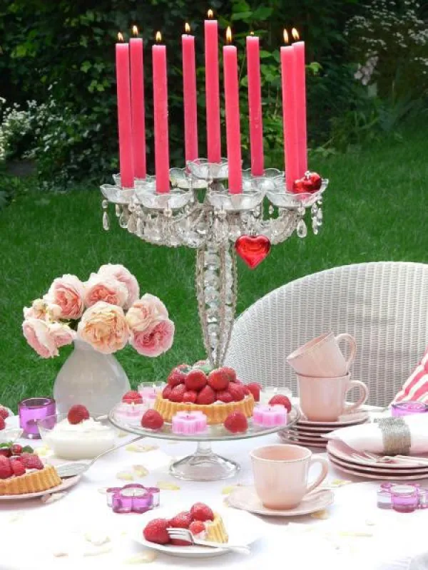An einem verführerisch gedeckten Tisch in Weiß und Rosé schmeckt die Erdbeertorte besonders köstlich. Fotovermerk: Gütegemeinschaft Kerzen