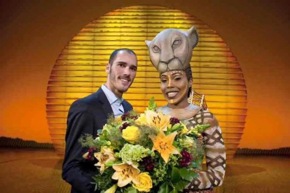 Jessica Mears, die im Musical die Hauptrolle der Nala spiel, überreicht Christian Altenburger aus Zürich, dem 6-millionsten Besucher von Disneys DER KÖNIG DER LÖWEN, einen großen Strauß. (Copyright: S