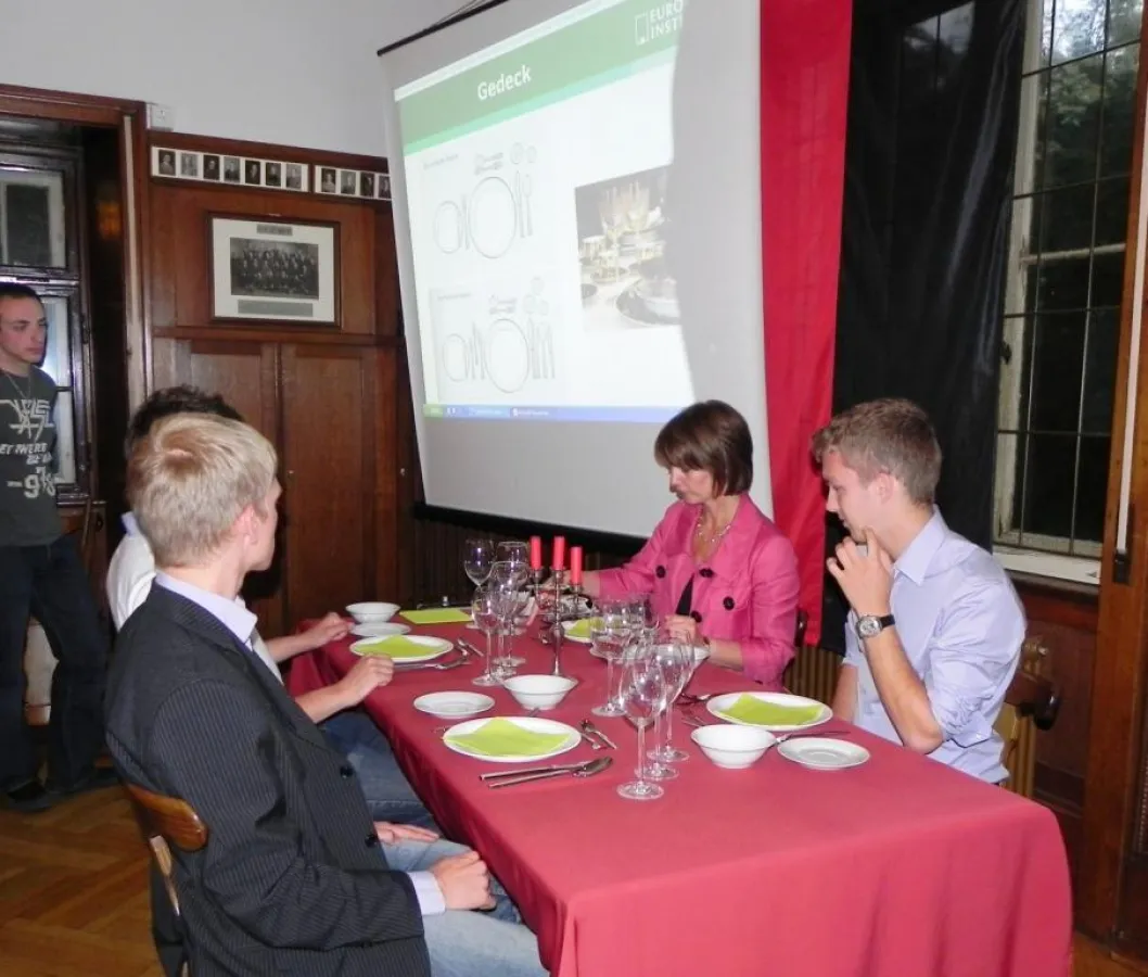 Seminarteilnehmer und Coach Mayer an der gedeckten Tafel - was gehört wohin?