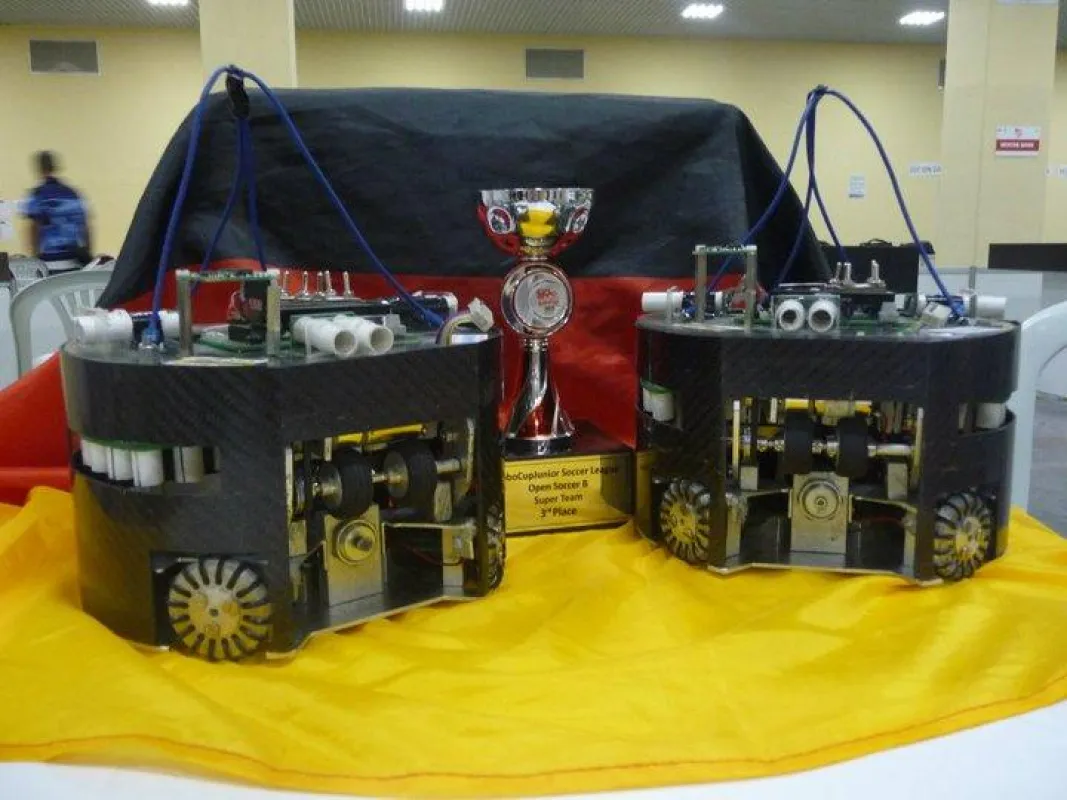 Die Roboter des siegreichen Teams zusammen mit dem errungenen Pokal
