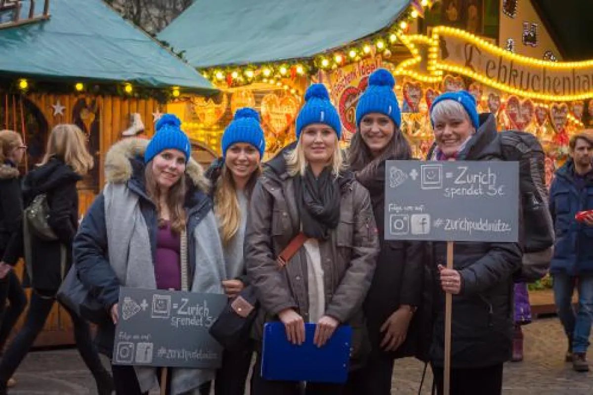 Zurich Team verteilt die Pudelmützen auf dem Bonner Weihnachtsmarkt