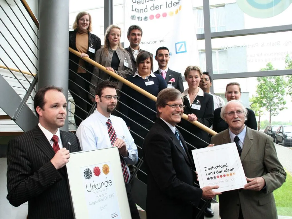 Eckhard Krois (1. v. l.) und Reinhard Krella (2. v. r.) von der Deutschen Bank Bochum überreichen Prof. Dr.-Ing. Dietrich Stein (1. v. r.) und dem UNITRACC-Team die Urkunde und Ehrentafel zum \