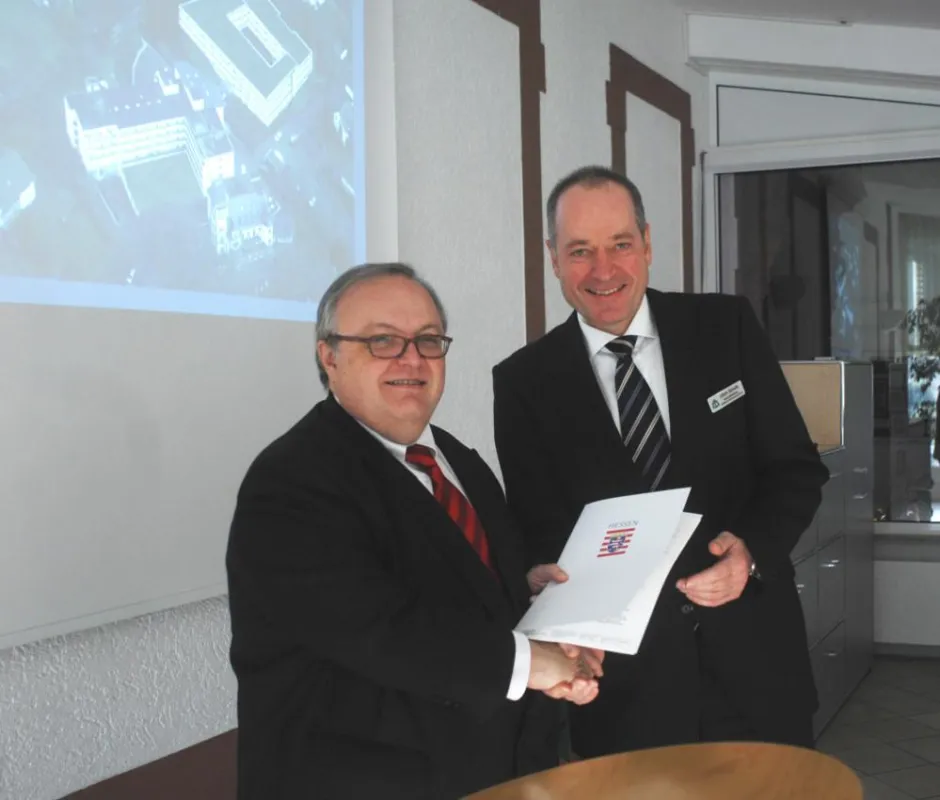 Das Bild zeigt den hessischen Gesundheitsminister Jürgen Banzer (links) bei der Übergabe des Bewilligungsbescheides an Geschäftsführer Ulrich Schultz.