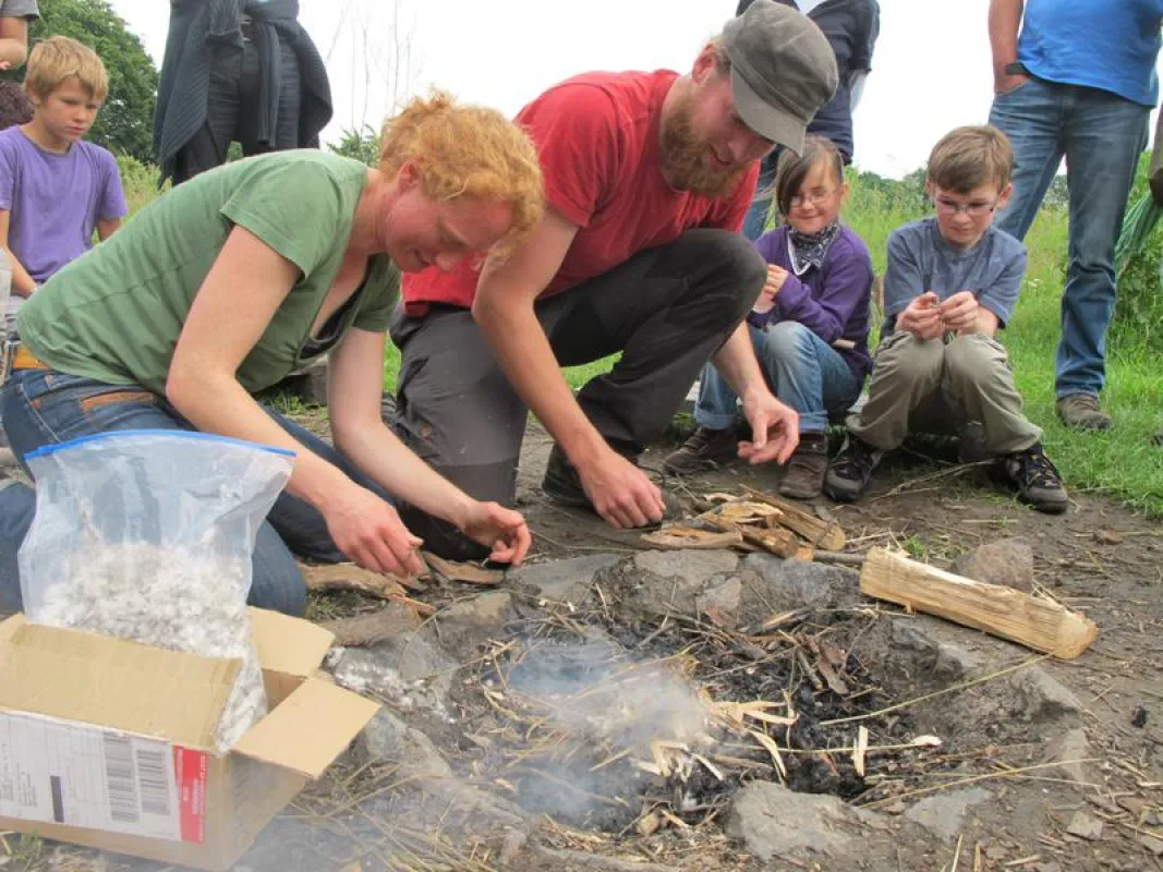 Entspannte Freude beim Sommerfest, die Kinder lernen wie man ohne Streichhölzer Feuer machen kann.