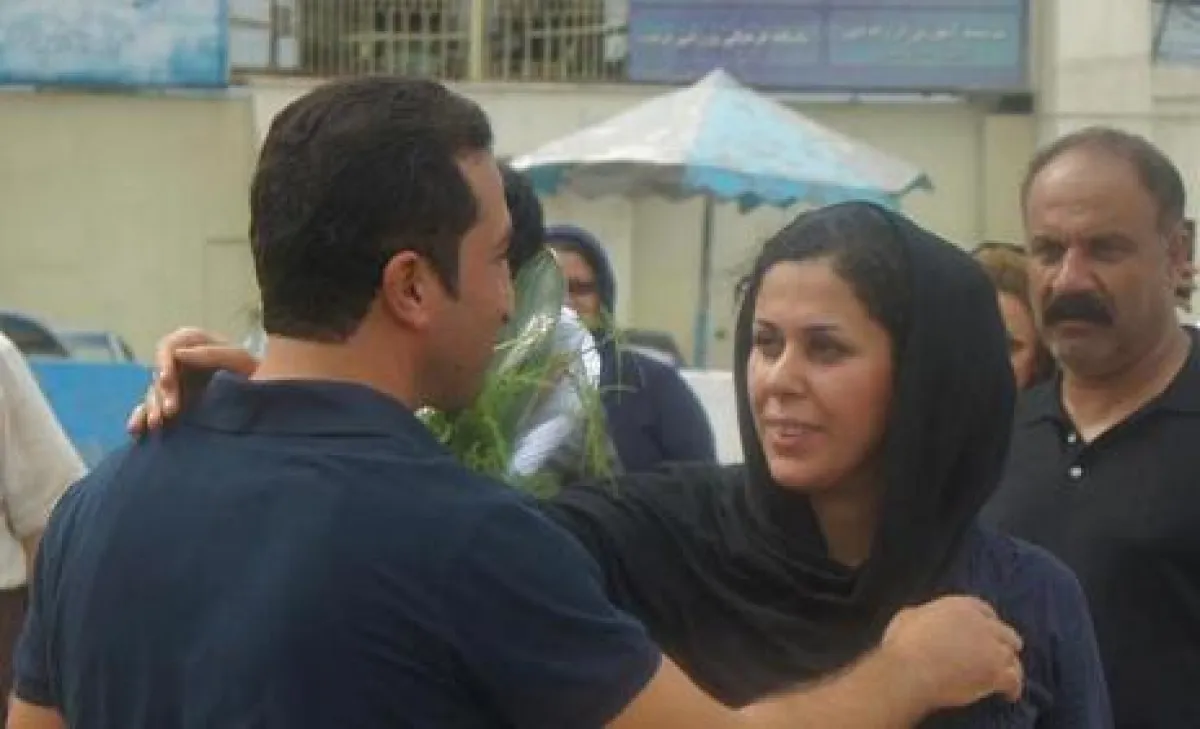 Nadarkhani umarmt seine Frau. Im Hintergrund das Gefängnis