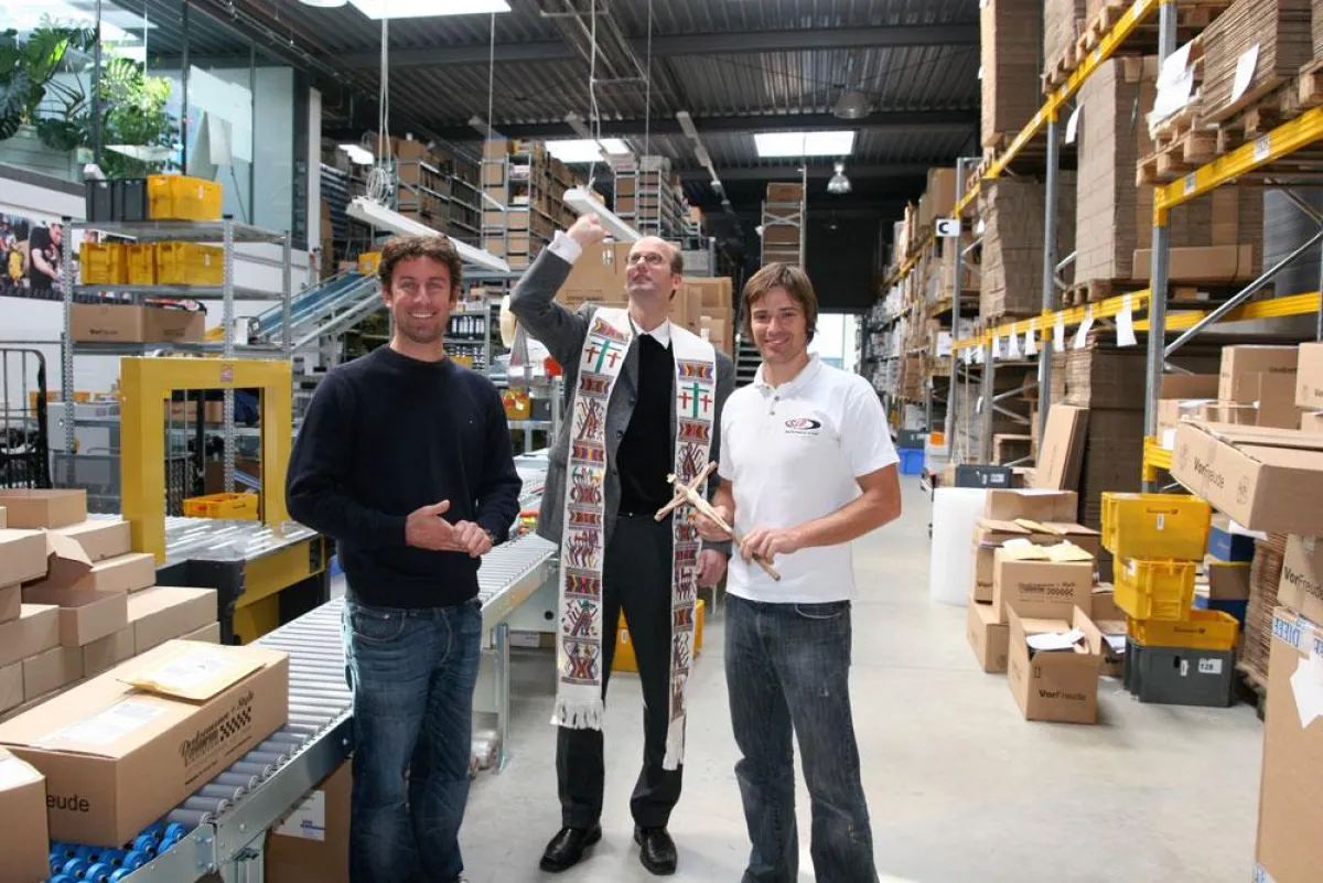 Stadtpfarrer Rauch weiht die moderne Logistikanlage ein. Daneben (links) Ralf Jodl und (rechts) Alexander Barth, die Inhaber.