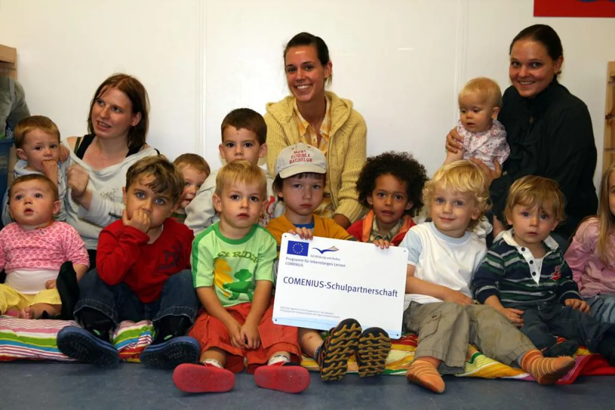 Stolz präsentieren die Little Giants Kinder und Mitarbeiter das COMENIUS-Schild