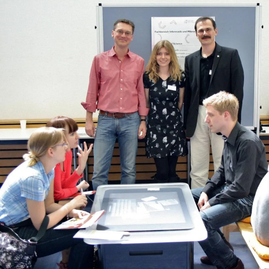 Die Preisträger Prof. Wallach, Simone Hamm und Prof. Schiefer hinter dem ixMentor-Beratungstisch, der am 24. April beim Offenen Campus zum ersten Mal zum Einsatz kam.