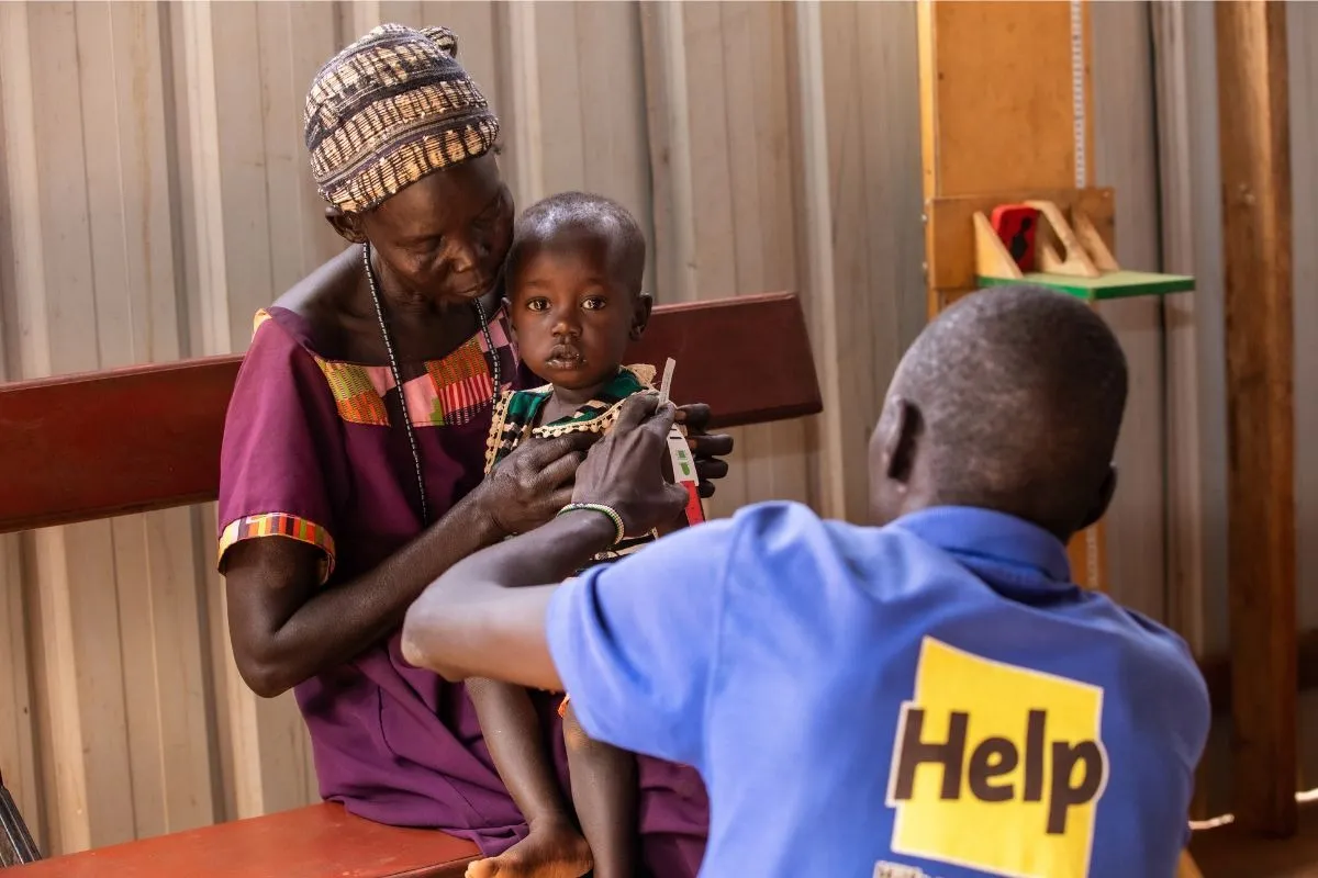 Ein Mitarbeiter von Help untersucht ein Kind auf Anzeichen von Unterernährung. (© Padi Pictures / Help - Hilfe zur Selbsthilfe)