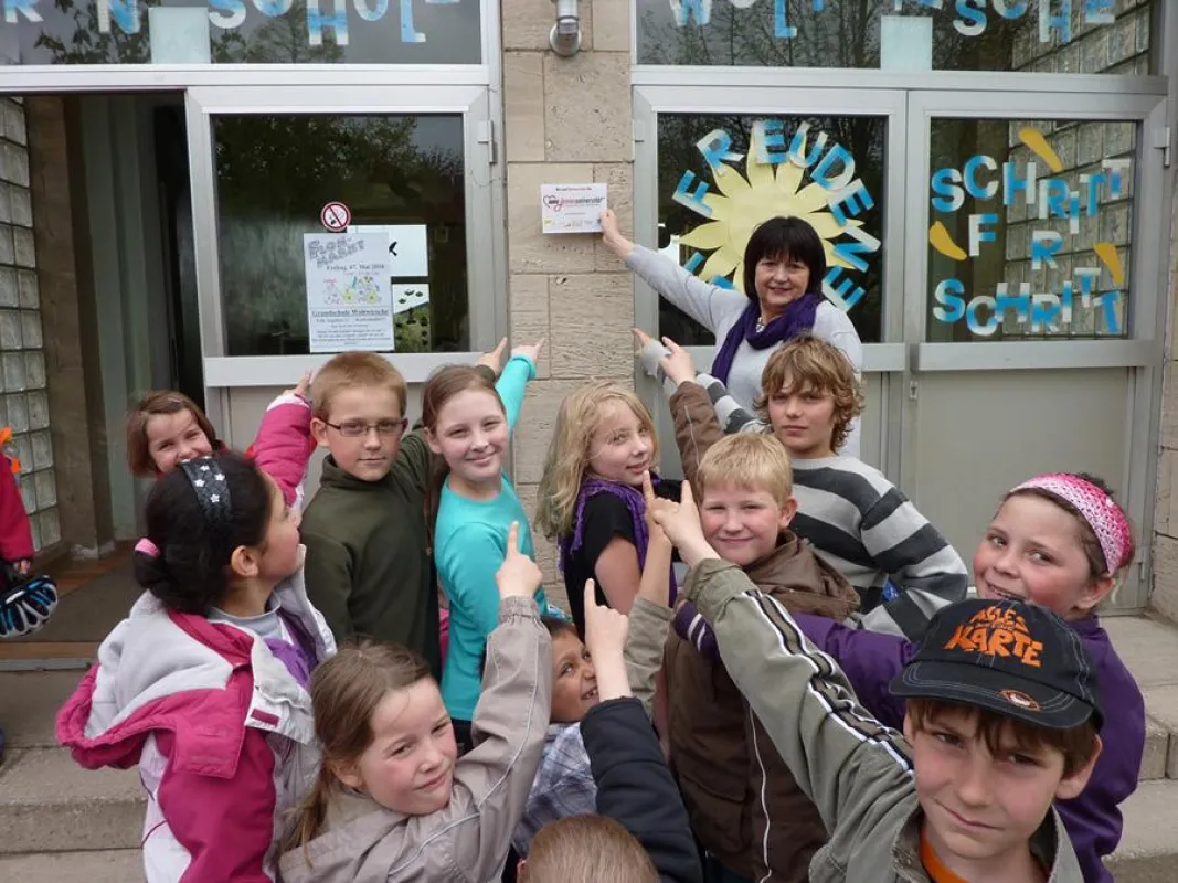 Auf die Partnerschaft mit der AWO Junioruniversität wird mit einem Schild am Eingang der Schule hingewiesen. Die Schulkinder haben diesen Ort ausgesucht. Foto: AWO Junioruniversität